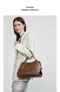 Détail du sac à main en cuir marron foncé avec boucle latérale et breloque métallique