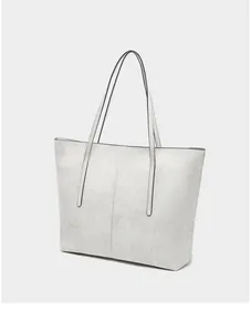 Detailed view of large off-white tote bag showing pebbled texture and long shoulder strap