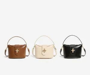 Three leather bucket bags in brown, beige, and black with elegant gold cross locks