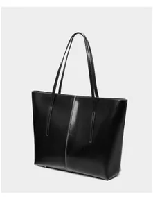 Macro detail of high-quality black leather tote bag showing protective metal bottom studs