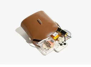 Top view of brown leather bucket bag showing interior space with phone and makeup items