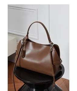 Détail du sac cabas en cuir marron avec boucle argentée sur un tabouret moderne