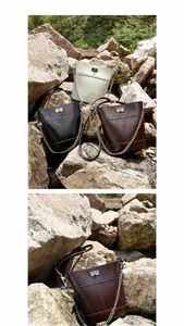 Vue détaillée de sacs seau à chaîne blancs, noirs et café sur un socle en pierre naturelle