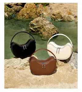 Outdoor shot of three minimalist leather crescent bags in black, beige, and brown colors