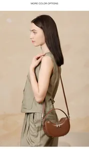 Detail of brown leather half-moon bag with silver zipper and detachable strap on model