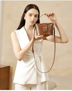 Detail of premium brown leather handbag featuring a polished gold oval twist lock