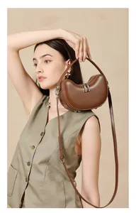 Brown leather crescent bag detail shown with adjustable strap and dual zipper closure