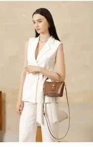 Detailed close-up of brown leather bucket bag with gold twist lock and protective feet