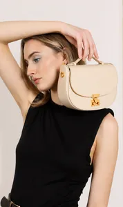 Detail of a beige cowhide leather saddle bag featuring a gold metal buckle closure