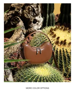 Detailed view of the dark brown leather dumpling bag with silver zippers in nature