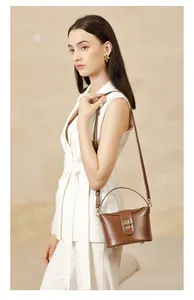 Detailed close-up of brown leather handbag with gold capsule lock on textured background