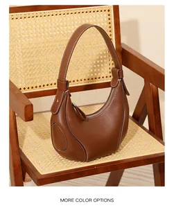Dettaglio borsa a mezzaluna in pelle marrone con cuciture bianche su sedia vintage