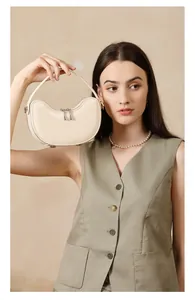 Detail view of cream leather dumpling bag with silver zippers and protective metal feet