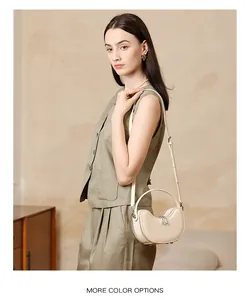 Detail of minimalist beige leather moon bag showing smooth matte texture and curved handle
