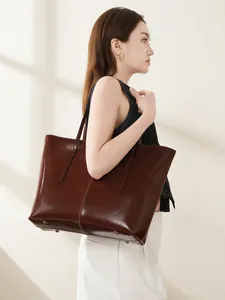 Large vintage brown leather tote bag with glossy finish shown in minimalist lifestyle setting
