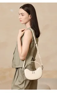 Close-up of beige leather dumpling bag with metal ring handle and adjustable strap