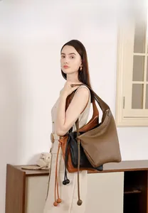 Tre borse a tracolla in pelle minimaliste in verde, nero e marrone indossate da una modella
