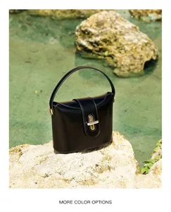 Detail of black leather handbag featuring a golden cylindrical lock and fine stitching