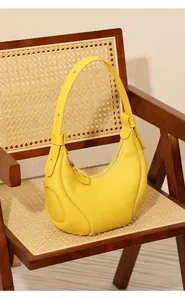 Dettaglio borsa hobo gialla con cuciture a contrasto su una sedia in vimini