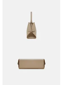 Vue détaillée du sac à main en cuir beige montrant le profil et la structure de la base