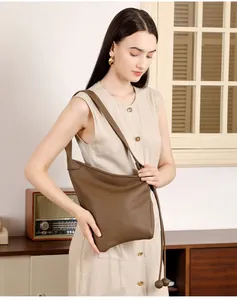 Dettaglio della texture in pelle a grana litchi con nappa a sfera sulla borsa marrone scuro