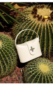 Detail of cream leather handbag with gold cross lock and elegant curved handle