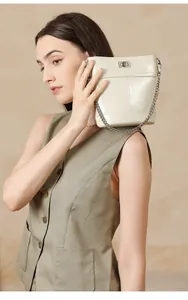 Détail d'un sac seau beige en cuir ciré avec fermoir rotatif argenté et bandoulière