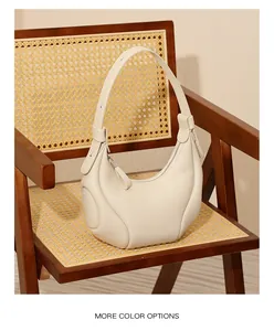 Dettaglio della borsa a mezzaluna bianco crema in pelle martellata su sedia vintage