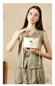 Detail of cream leather handbag featuring a golden capsule twist lock and structured handle