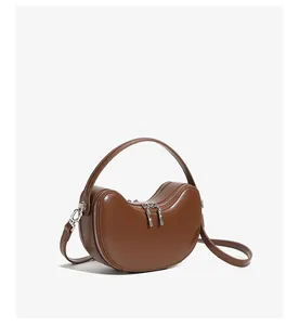 Macro view showing the glossy finish and premium leather texture of the brown crescent bag