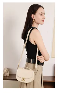 Close-up of cream leather crescent bag with golden twist-lock and shoulder strap detail