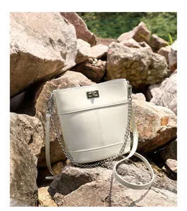 Détail du sac seau en cuir ciré crème avec fermoir rotatif argenté et bandoulière chaîne