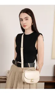 Close-up of cream leather saddle bag with gold metal buckle and adjustable strap details