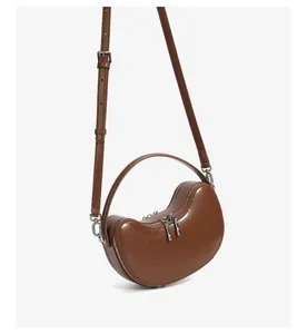 Detailed side view of dark brown leather dumpling bag with silver double zippers