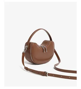Side view of dark brown leather half-moon bag showing double zippers and shoulder strap