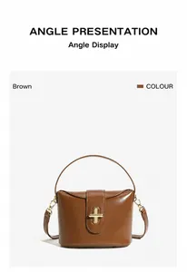 Detail of a brown leather handbag featuring a golden swivel lock and detachable strap