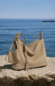 Dettaglio borsa tote in pelle martellata kaki con portamonete su rocce costiere