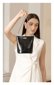 Vue détaillée du sac seau en cuir verni noir avec fermoir rotatif argenté et chaîne