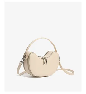 Detailed view of the creamy crescent leather bag showing smooth texture and silver zippers
