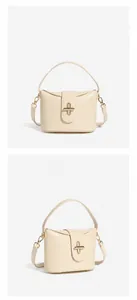 Detail view of the cream white leather handbag with golden metal cross lock and top handle
