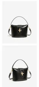 Detailed view of black structured leather handbag with golden capsule lock and top handle