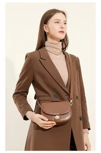 Close-up of dark brown leather saddle bag with gold metal buckle and textured finish