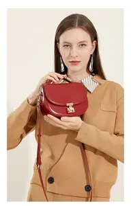 Detail of burgundy leather half-moon saddle bag with gold metal buckle and shoulder strap