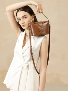 Brown leather structured handbag with gold twist lock and shoulder strap on model