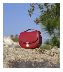 Detail view of red leather crescent bag with gold buckle on a natural rock background