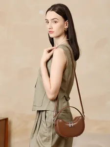 Dark brown leather crescent crossbody bag styled with a professional green vest suit