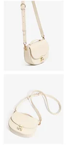 Detail showing the cream leather texture and gold metal push-lock closure of the moon bag