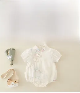 Flat lay of vintage floral baby girl romper with mandarin collar and frog button details