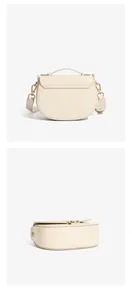 Macro detail of off-white leather saddle bag with polished gold-tone metal hardware and strap