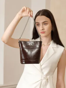 Sac seau élégant en cuir ciré marron foncé avec bandoulière chaîne et fermoir argenté